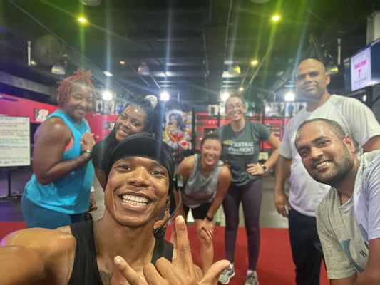 A vibrant group of people smiling and posing together in a gym environment, showcasing camaraderie and teamwork after a fitness session.